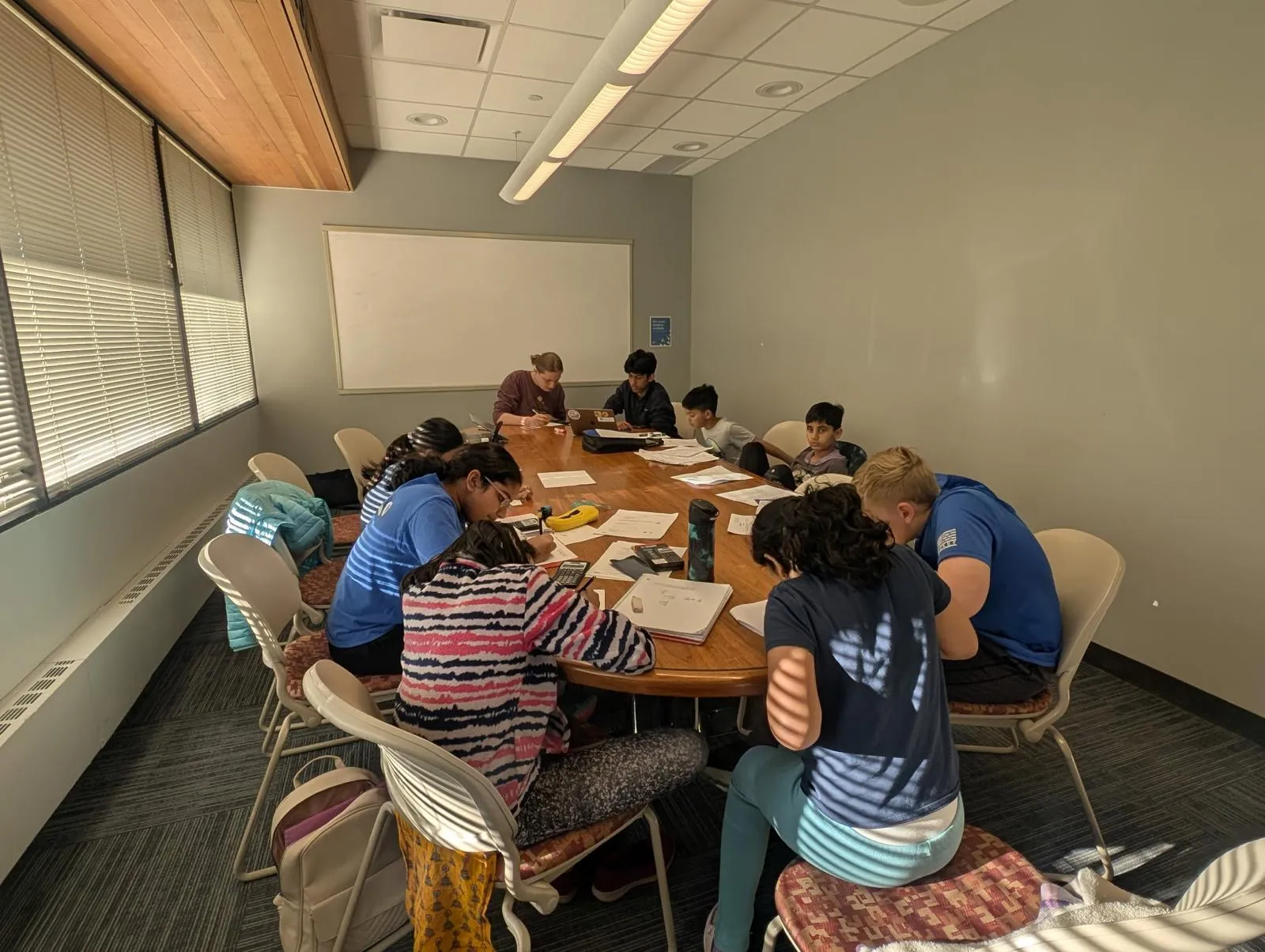 A coaching session: students working through problems around a table with their high-school mentors